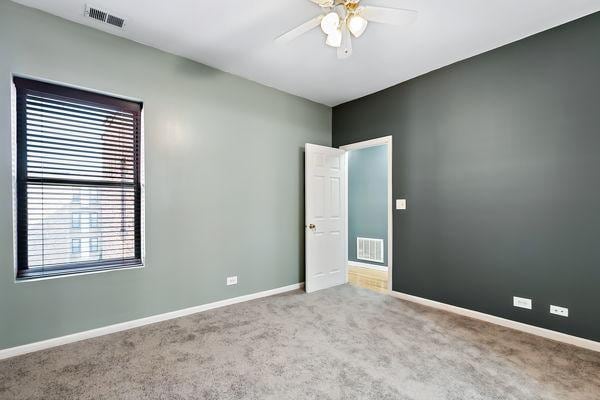 carpeted spare room featuring ceiling fan