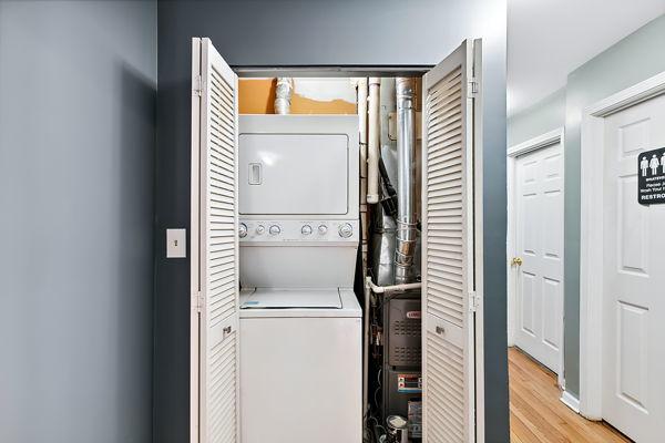 clothes washing area featuring stacked washer / dryer and light hardwood / wood-style floors