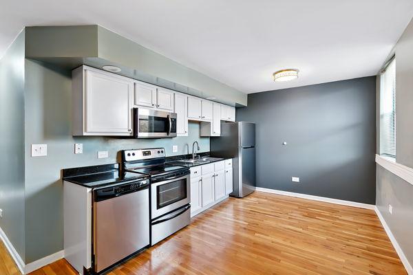 kitchen with stainless steel appliances, light hardwood / wood-style floors, and white cabinets