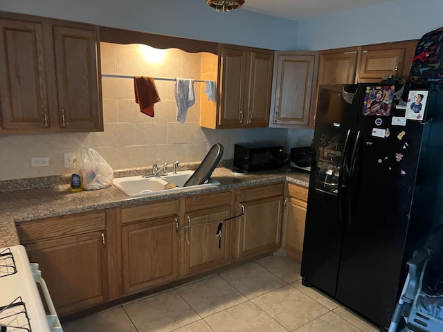 kitchen featuring backsplash, black appliances, sink, and light tile flooring