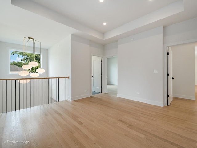 unfurnished room with light hardwood / wood-style flooring and a raised ceiling