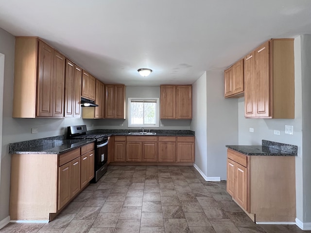 kitchen with gas stove, sink, tile floors, and dark stone counters