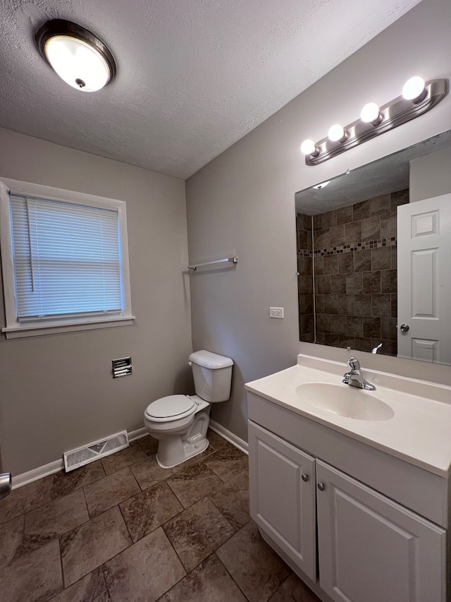 bathroom featuring tile flooring, vanity, toilet, and a textured ceiling