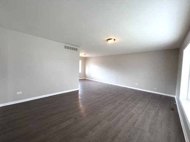 empty room with dark hardwood / wood-style flooring and a wealth of natural light