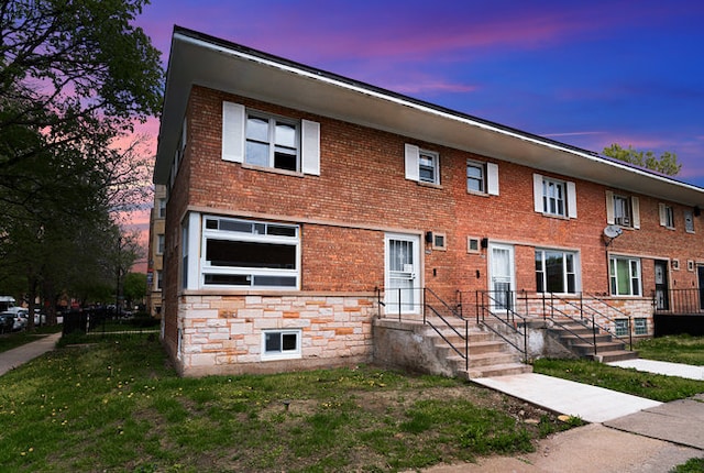 townhome / multi-family property featuring a front yard, stone siding, and brick siding