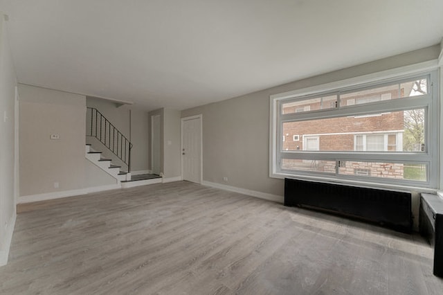 unfurnished room featuring light wood-type flooring and radiator heating unit