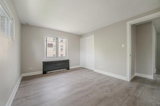 spare room featuring radiator heating unit, baseboards, and wood finished floors