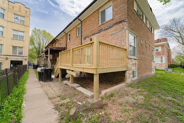 rear view of house with fence, a deck, and brick siding