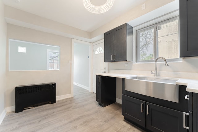 kitchen featuring sink, a healthy amount of sunlight, radiator heating unit, and light wood-type flooring