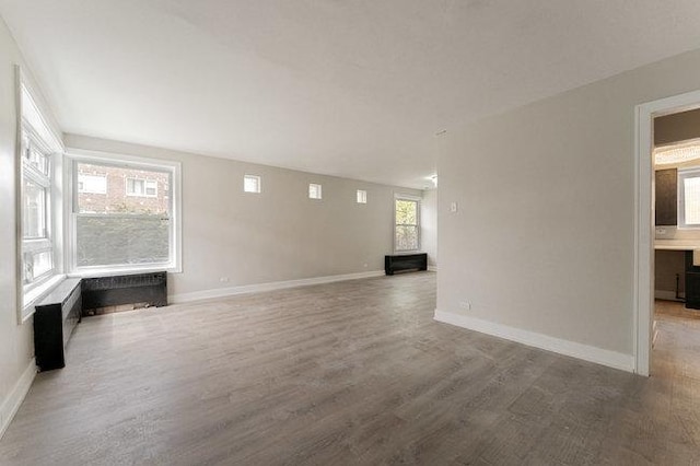 unfurnished living room with baseboards and wood finished floors