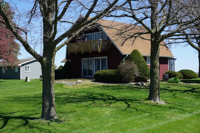 rear view of property featuring a yard, a balcony, and central air condition unit