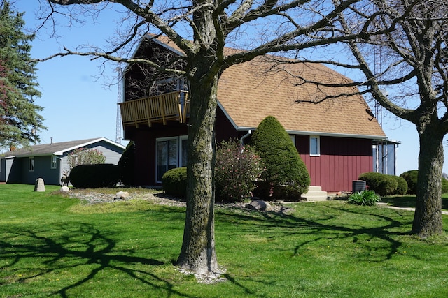 view of side of home featuring a yard, central AC, and a balcony