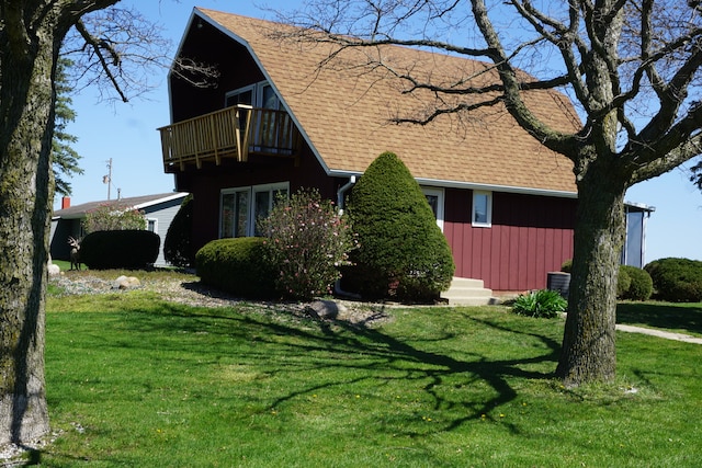 view of side of property featuring a balcony, a lawn, and central air condition unit