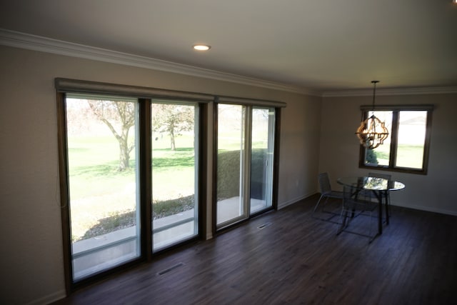 doorway with a chandelier, crown molding, and dark wood-type flooring