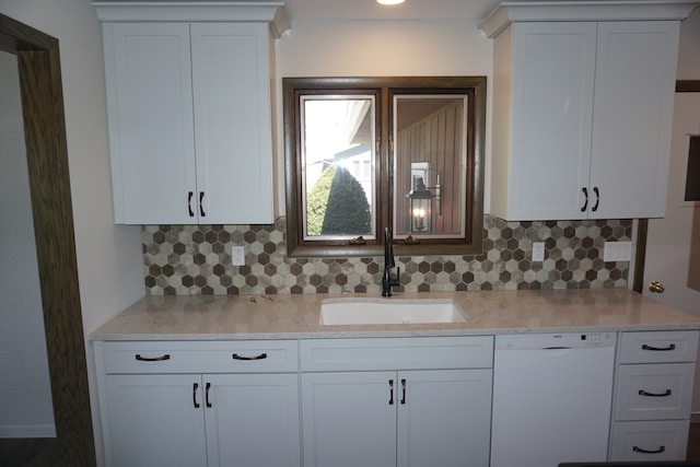 kitchen featuring backsplash, sink, white dishwasher, and white cabinetry