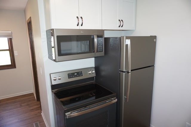 kitchen featuring stainless steel appliances, dark hardwood / wood-style flooring, and white cabinetry