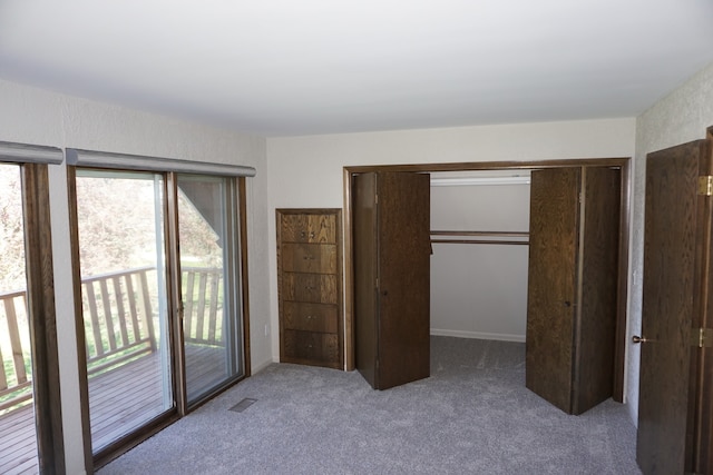 unfurnished bedroom with a closet, dark colored carpet, a walk in closet, and access to outside