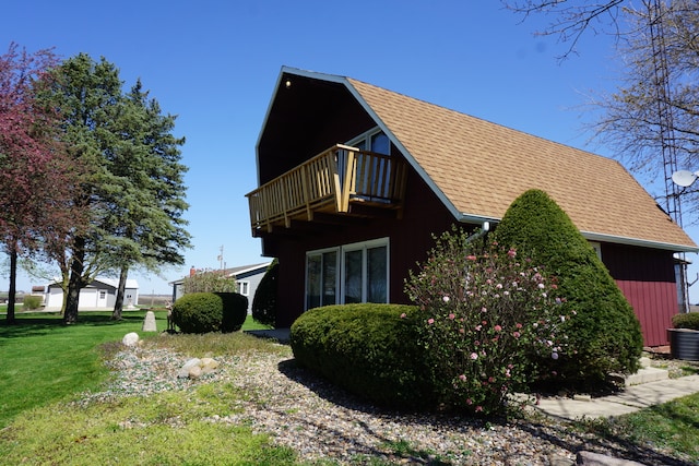 view of side of property featuring a balcony and a lawn