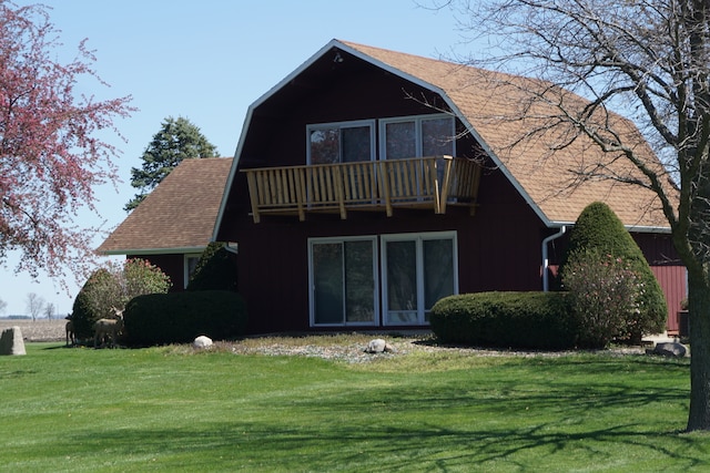 rear view of property featuring a balcony and a lawn