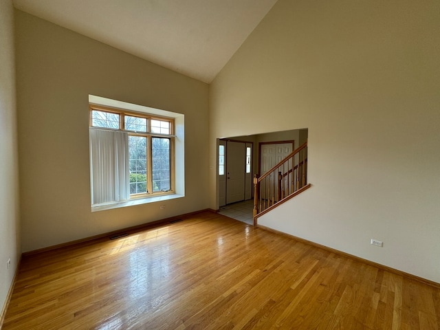 unfurnished room featuring light hardwood / wood-style flooring and high vaulted ceiling