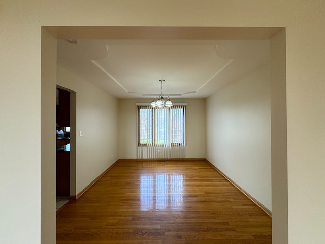 spare room with a notable chandelier and hardwood / wood-style flooring