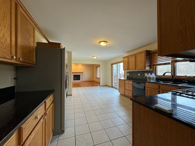 kitchen with sink, backsplash, light tile flooring, dark stone counters, and black dishwasher