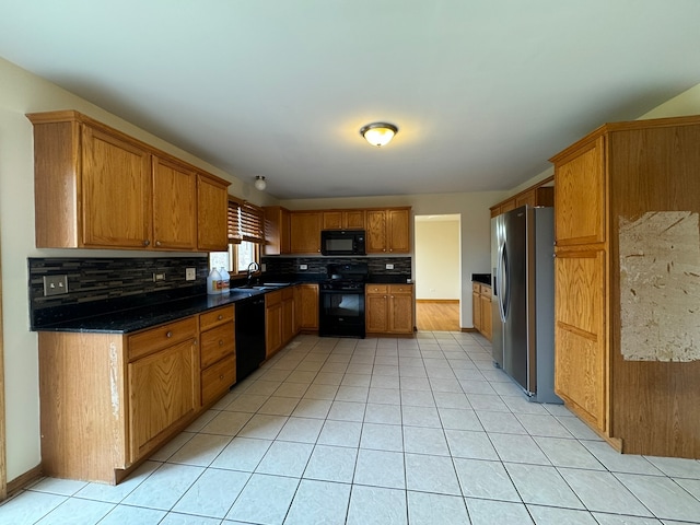 kitchen with backsplash, light tile flooring, black appliances, dark stone countertops, and sink