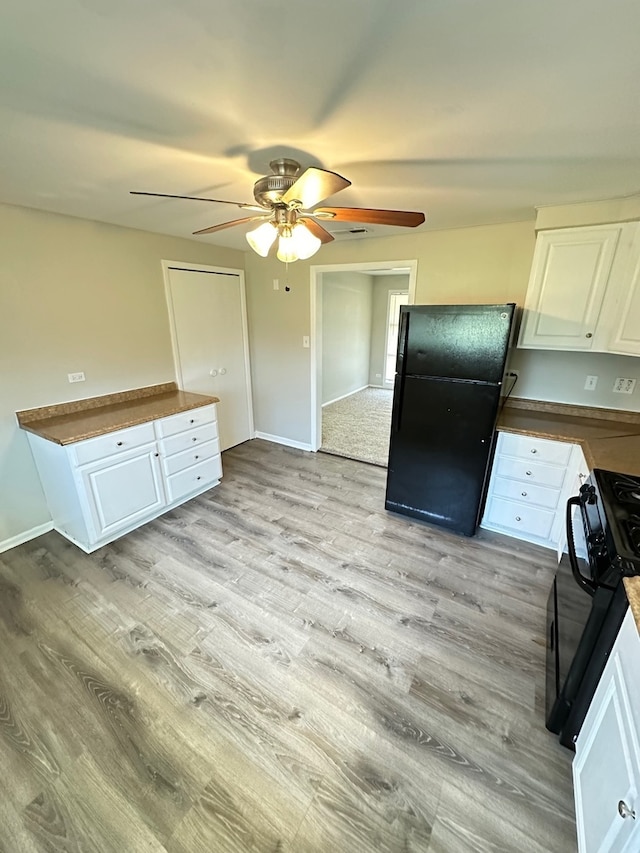 kitchen featuring black fridge, light hardwood / wood-style flooring, ceiling fan, range, and white cabinetry