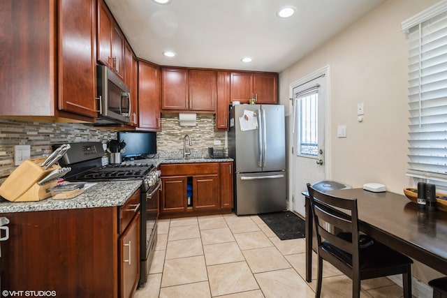 kitchen featuring light stone counters, stainless steel appliances, sink, light tile floors, and tasteful backsplash