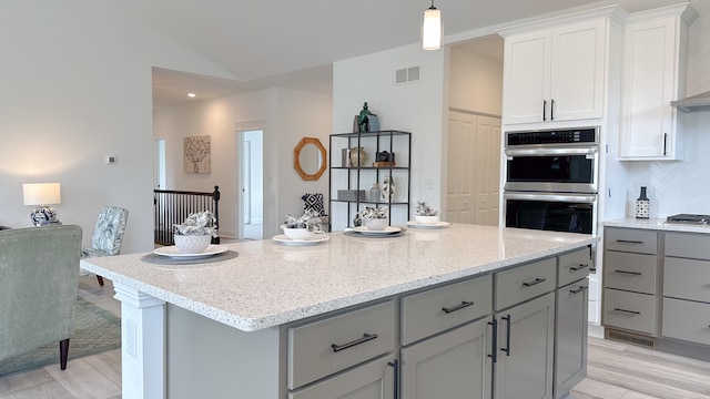 kitchen with tasteful backsplash, visible vents, wall chimney exhaust hood, hanging light fixtures, and stainless steel appliances