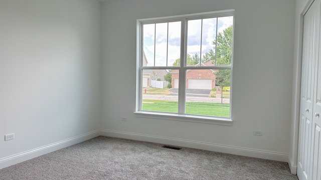 empty room featuring carpet floors, visible vents, and baseboards