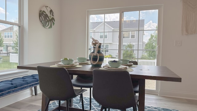 dining space with light wood-type flooring and baseboards