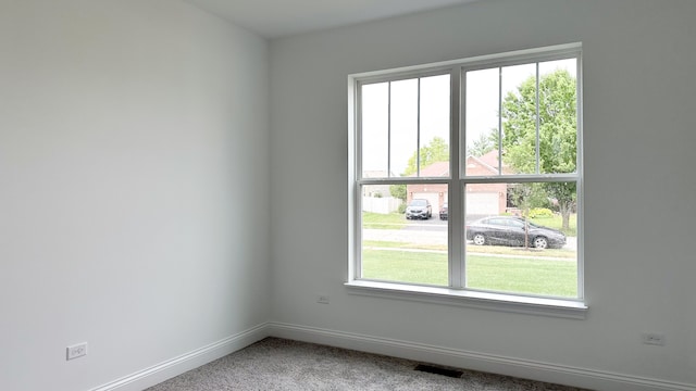 empty room with carpet floors, visible vents, and baseboards