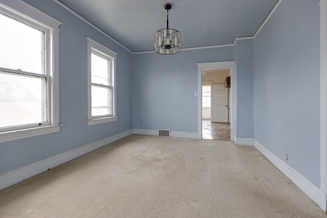 empty room featuring ornamental molding, an inviting chandelier, and light carpet