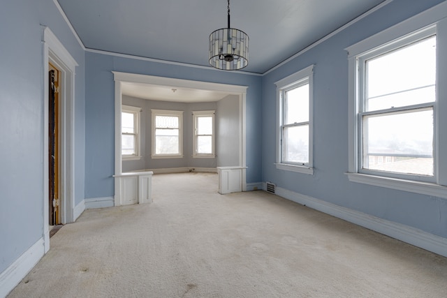 carpeted spare room featuring a notable chandelier and crown molding