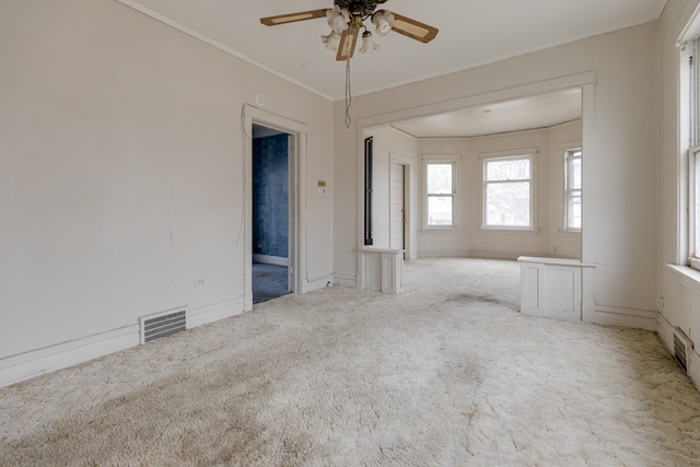 empty room featuring crown molding, ceiling fan, and carpet floors