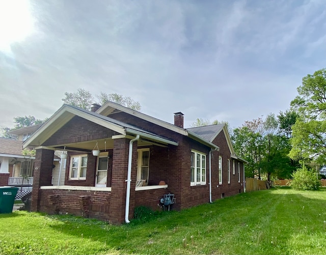 view of side of property featuring covered porch and a lawn