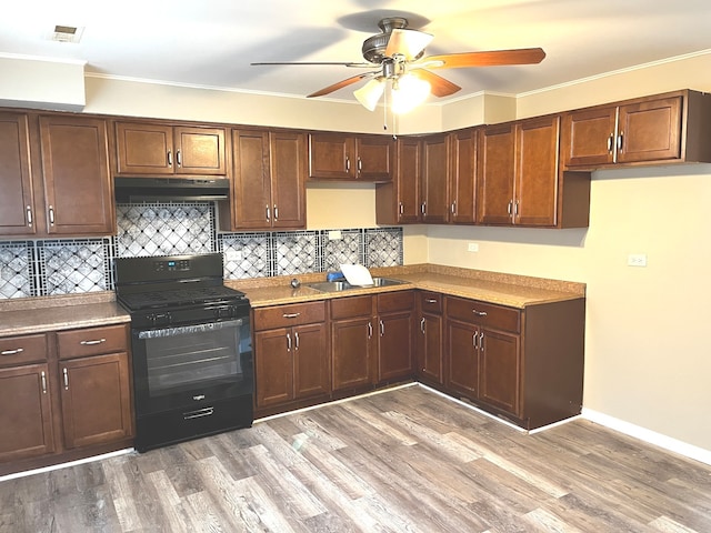 kitchen featuring ceiling fan, sink, backsplash, black range oven, and wood-type flooring