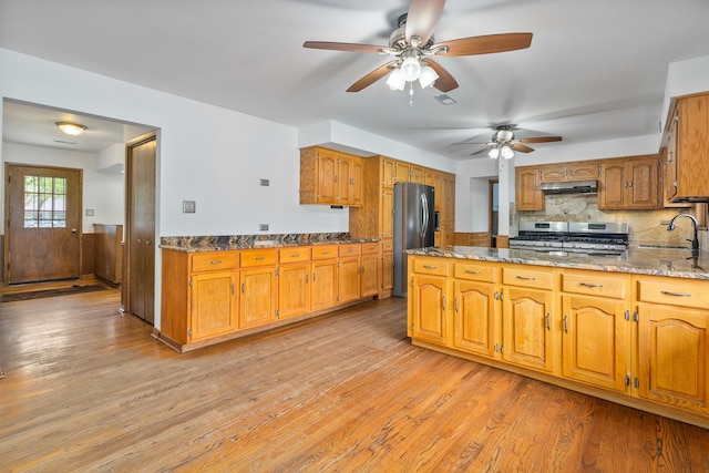 6840 157th St, Tinley Park, IL 60477 - kitchen featuring stainless steel appliances, a ceiling fan, light wood-style flooring, dark stone countertops, and brown cabinetry