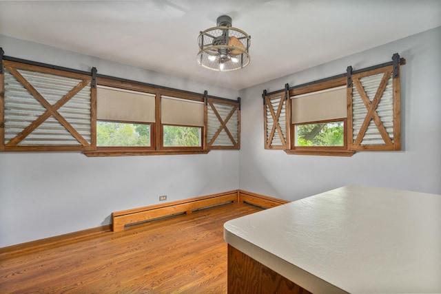6840 157th St, Tinley Park, IL 60477 - unfurnished room featuring a barn door, a baseboard radiator, wood finished floors, and plenty of natural light