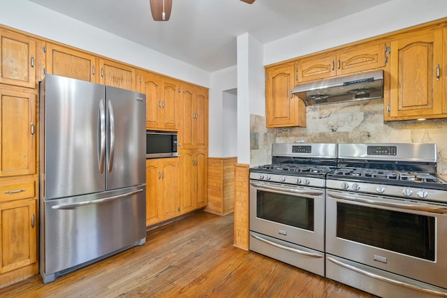 6840 157th St, Tinley Park, IL 60477 - kitchen with appliances with stainless steel finishes, under cabinet range hood, a ceiling fan, a wainscoted wall, and light wood-style floors
