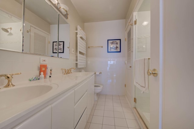 bathroom with a closet, tile walls, toilet, tile patterned flooring, and a sink