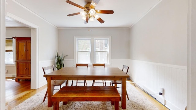 dining space with ornamental molding, wood-type flooring, and ceiling fan