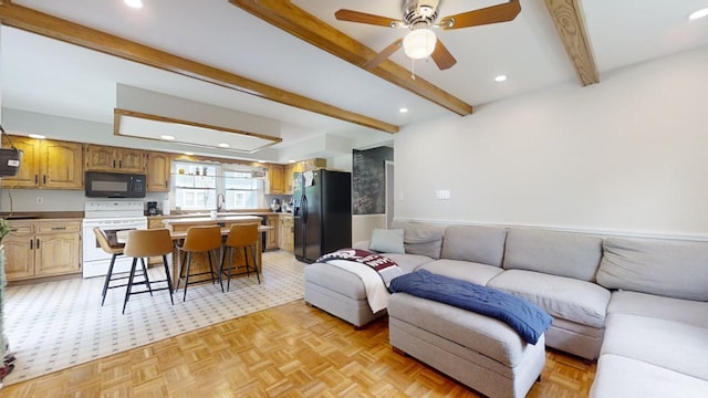 living room featuring light parquet floors, beam ceiling, ceiling fan, and sink