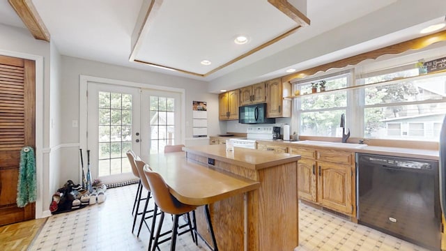 kitchen with a kitchen island, a breakfast bar, sink, black appliances, and french doors