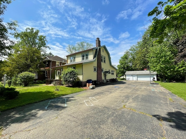 view of home's exterior featuring an outdoor structure, a garage, and a lawn