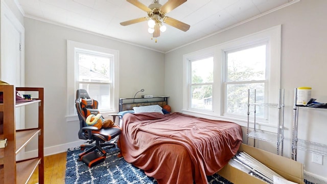 bedroom featuring hardwood / wood-style flooring, crown molding, ceiling fan, and multiple windows