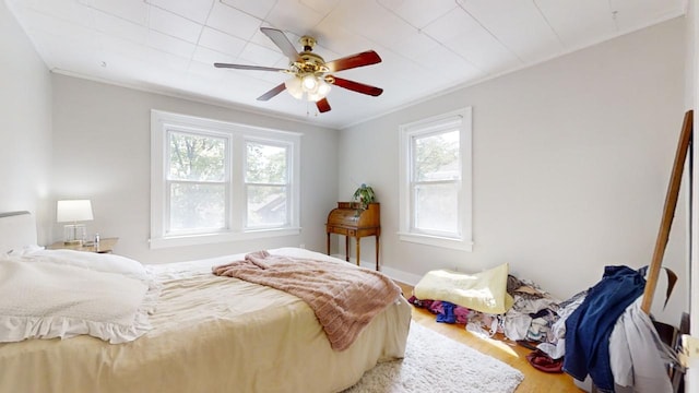 bedroom featuring wood-type flooring, ceiling fan, and crown molding