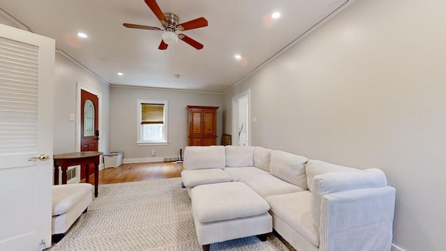 living room featuring wood-type flooring, ceiling fan, and ornamental molding