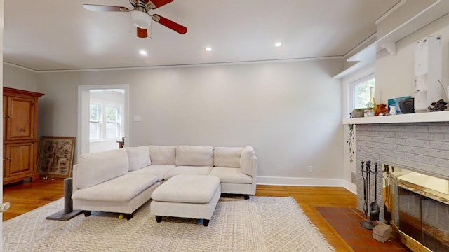 living room with ornamental molding, a brick fireplace, ceiling fan, and hardwood / wood-style floors